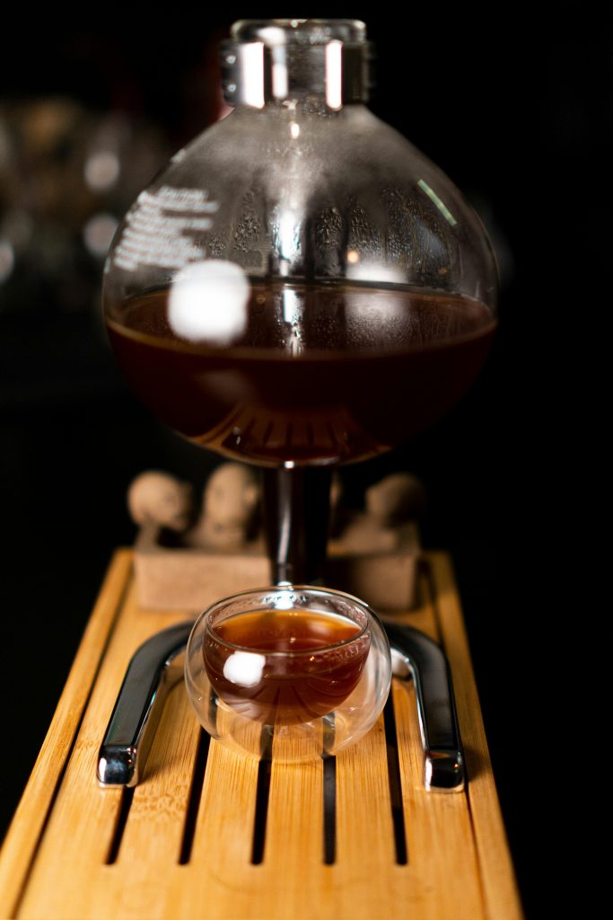 Close up of coffee siphon filling double walled glass espresso cup